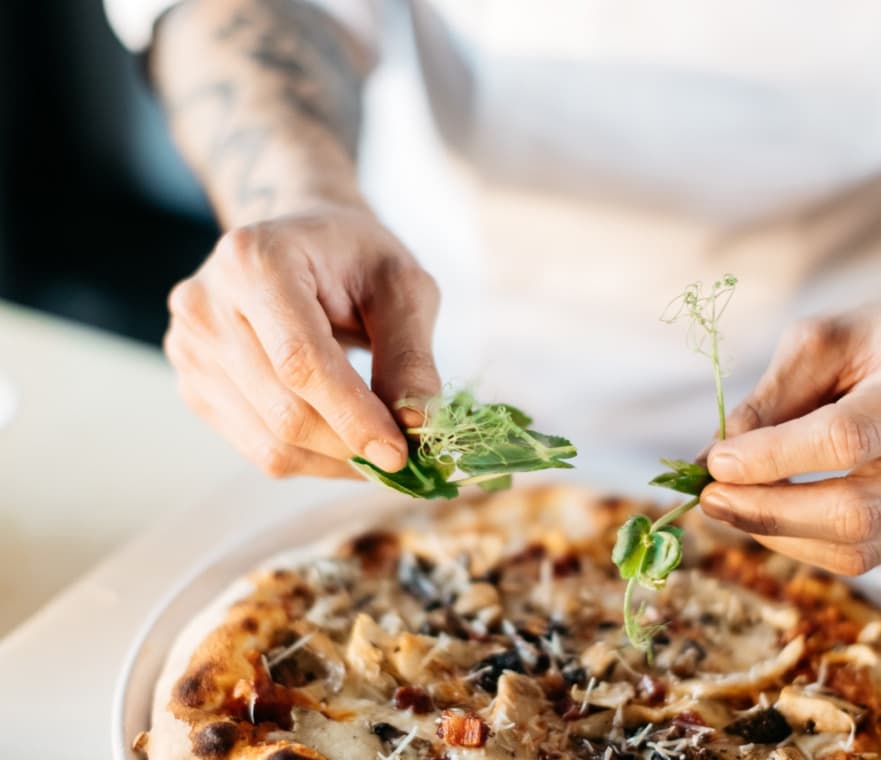 Koch richtet in der Küche des Da Zio eine frisch gebackene Pizza an